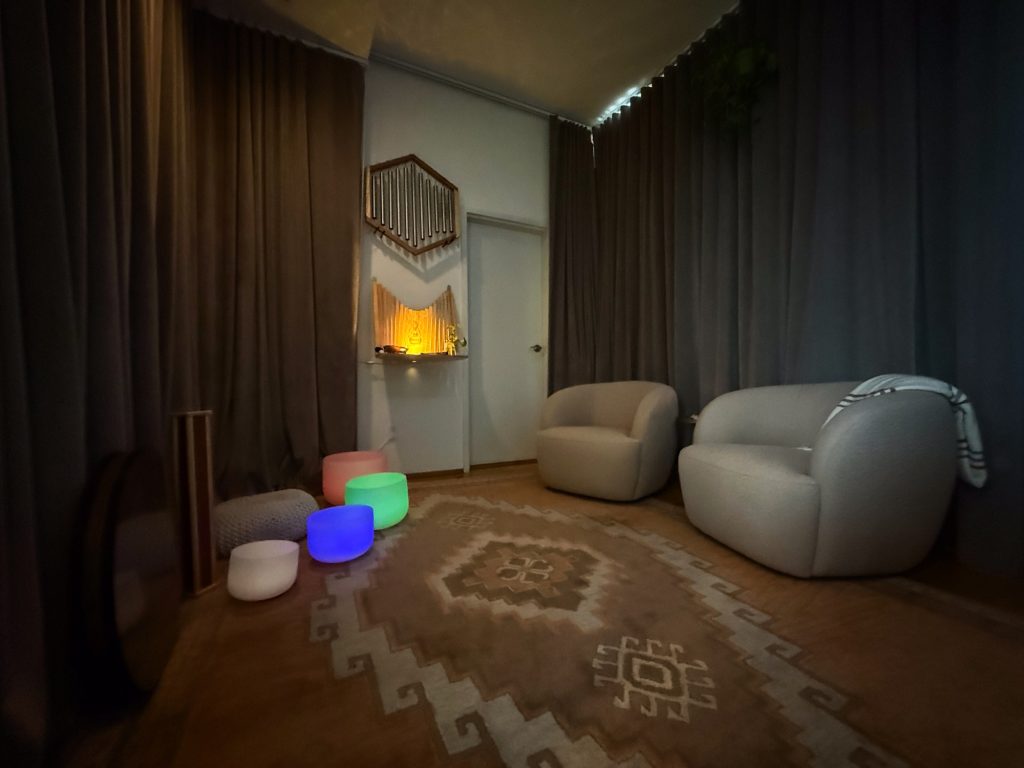 Dim healing lounge with glowing crystal bowls and cozy armchairs at Word of Mouth
